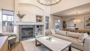 Een moderne woonkamer met een open haard, een bank, een salontafel en een eethoek.