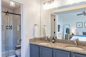 A bathroom with a double sink, a glass shower enclosure, and a large mirror. - Spacious 4BR Aurora Home with Sunroom and Fireplace (Aurora)