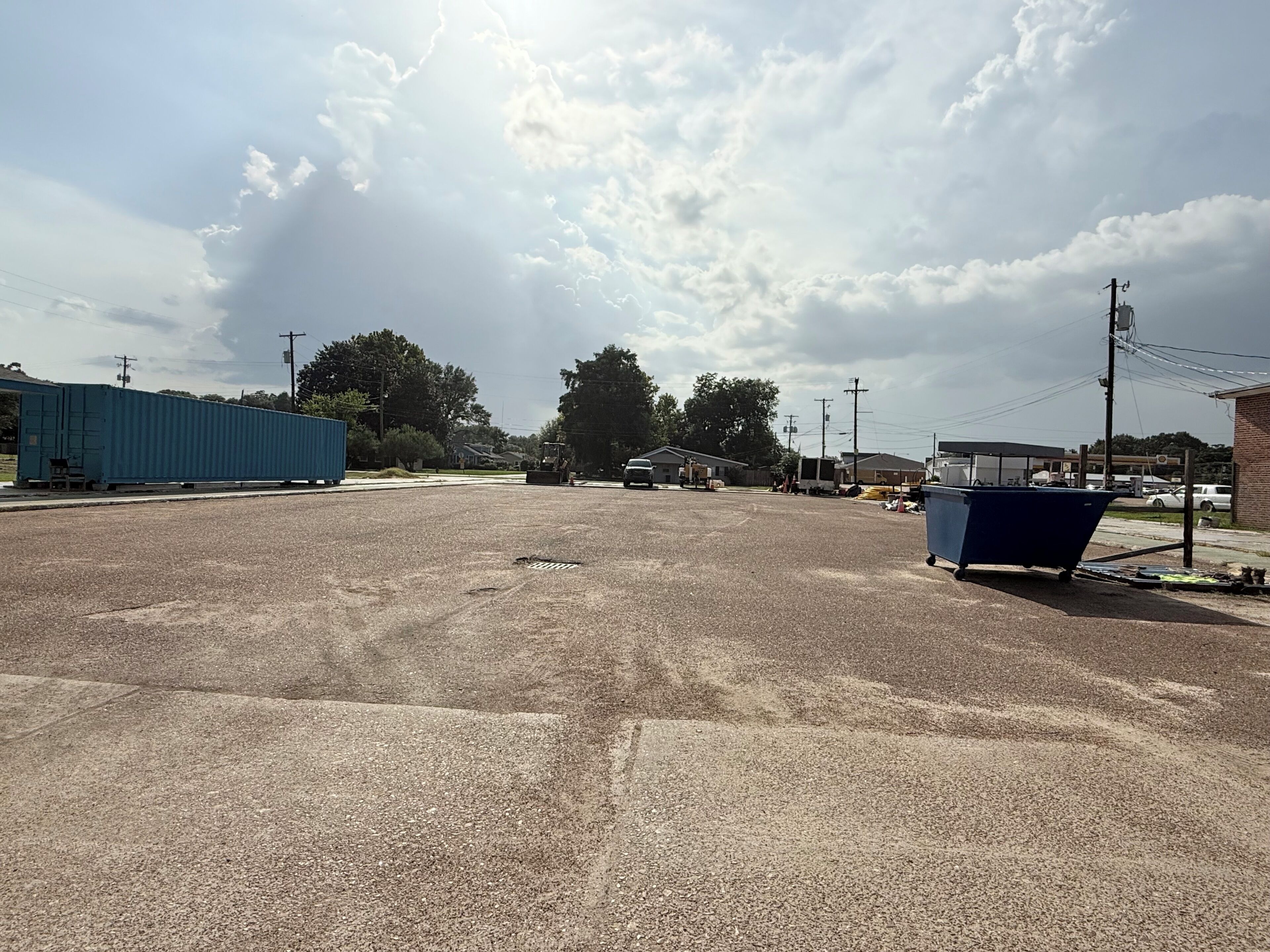 Un estacionamiento vacío con un contenedor de basura azul y un contenedor marítimo azul.