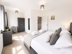 A modern bedroom with a large bed, bedside tables, a wardrobe, and a desk. - The Riverside • 4 Bedroom 4 Bathroom • New Build House • Sleeps 7 • Driveway Parking • Yoko Property (Huntingdon)