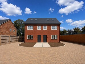 A two-story brick house with a front entrance, a driveway, and a fenced backyard. - The Riverside • 4 Bedroom 4 Bathroom • New Build House • Sleeps 7 • Driveway Parking • Yoko Property (Huntingdon)