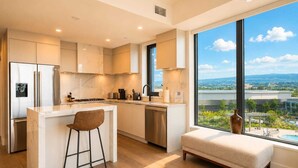 Cocina moderna con una isla grande, taburetes de bar y vistas a una piscina y paisaje.