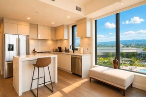 Une cuisine moderne dotée d’un grand îlot central, de tabourets de bar et offrant une vue sur une piscine et un paysage verdoyant.