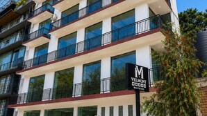 Ein mehrstöckiges Hotel mit Balkonen, ein Auto davor und ein Schild mit dem Hotelnamen.