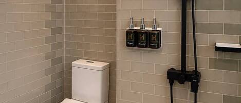 A modern bathroom with a toilet, a shower, and a shelf with toiletries.