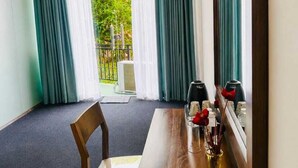 Ein Hotelzimmer mit Holztisch, einem Stuhl, einer Vase mit Blumen und einem Fenster mit Vorhängen.