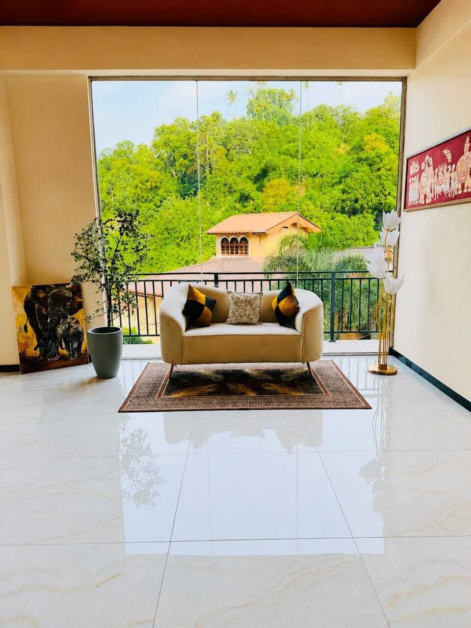 A spacious room with a large window, a sofa, a potted plant, and a framed picture on the wall.