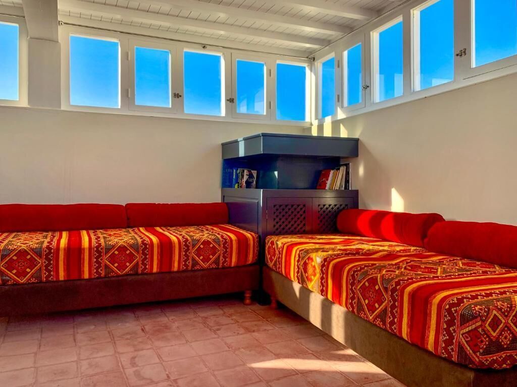 A room with two beds, a built-in bench, and a windowed ceiling.