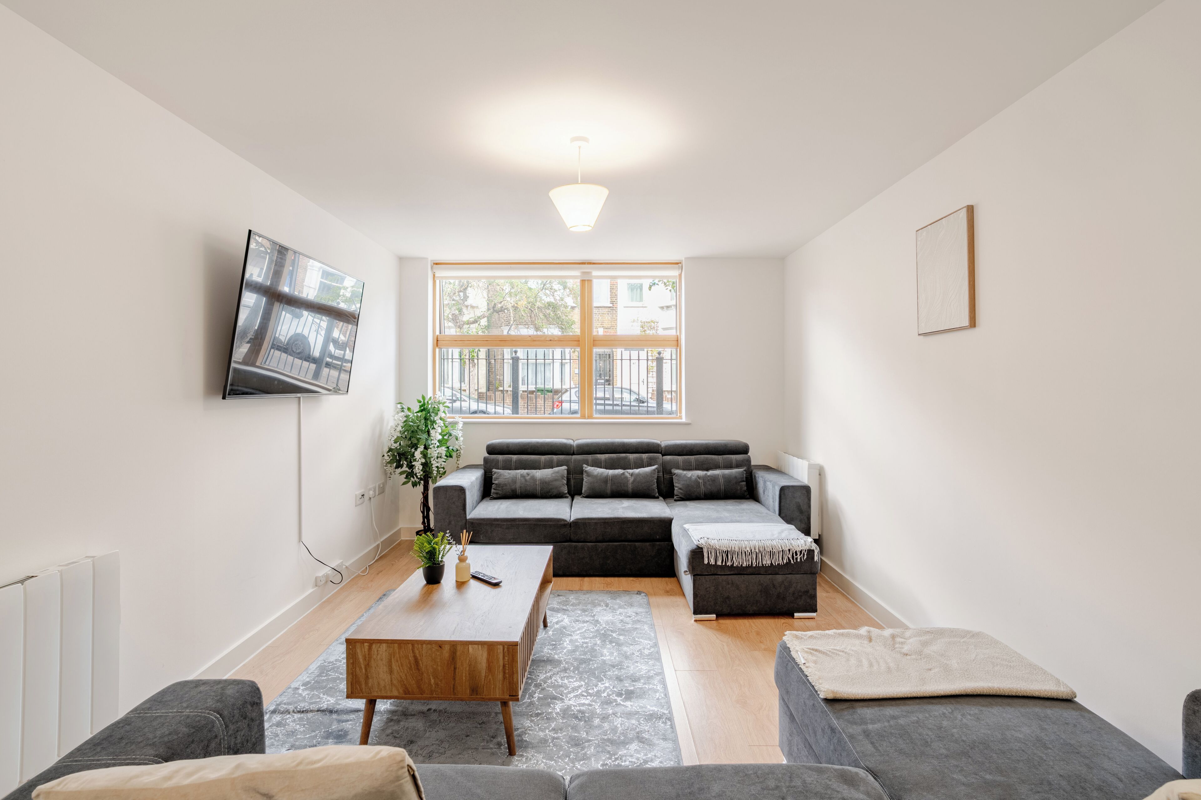 A modern living room with a sectional sofa, a coffee table, and a TV mounted on the wall.