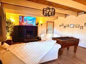 Ein gemütliches Zimmer mit einem Bett, einem Kicker, einem Fernseher und einem Kamin.