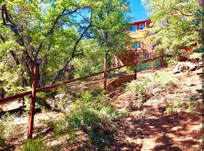A fenced outdoor area with trees and a building in the background. - Cozy place close to ski resorts, lake, town & golf (Big Bear)