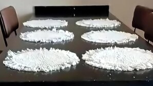 Une salle de conférence avec une table noire et six objets circulaires blancs posés dessus.