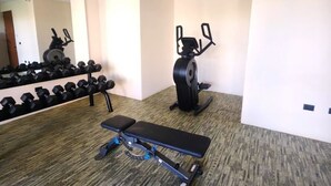 Une salle de sport équipée d’un banc de développé couché, d’haltères et d’un appareil de musculation elliptique.