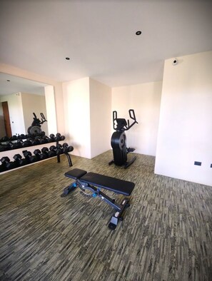 A gym with a bench press, dumbbells, and an elliptical machine. - Luxurious 2BR Penthouse-Tulum with private rooftop & pool. Great location/views. (Tulum)