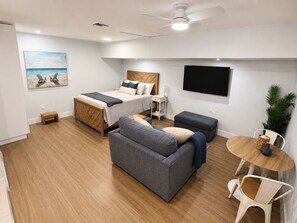 Un dormitorio moderno con cama, sofá, televisor y una mesita.