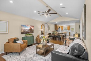 A spacious living area with a dining table, sofas, and a kitchen in the background.