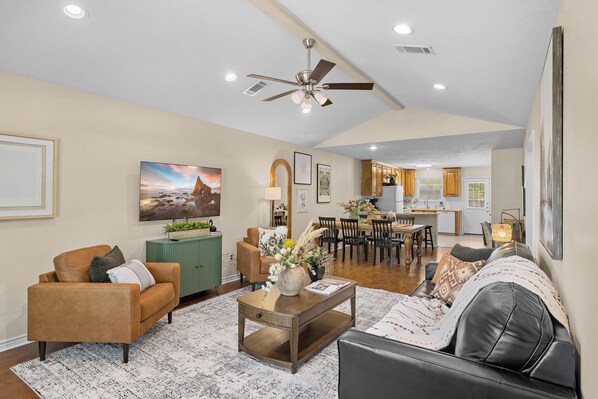 A spacious living area with a dining table, sofas, and a kitchen in the background.