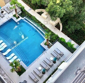 Ein Pool auf dem Dach mit Liegestühlen und Palmen.