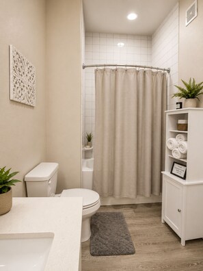 Ein Badezimmer mit Toilette, Waschbecken, Duschvorhang und einem Schrank mit Handtüchern.