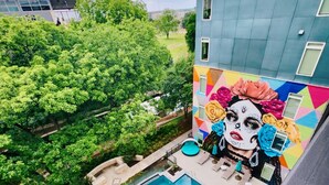 A rooftop pool with a mural, surrounded by greenery and a modern building. -     Luxury River Walk Retreat 2BR Downtown (San Antonio)