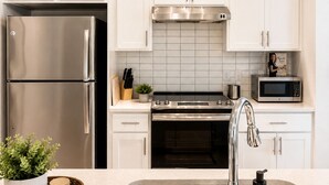 A modern kitchen with white cabinets, stainless steel appliances, and a central island with a sink. -     Luxury River Walk Retreat 2BR Downtown (San Antonio)