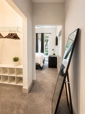 A hotel corridor with a bed, a desk, a mirror, and a clothing rack. -     Luxury River Walk Retreat 2BR Downtown (San Antonio)