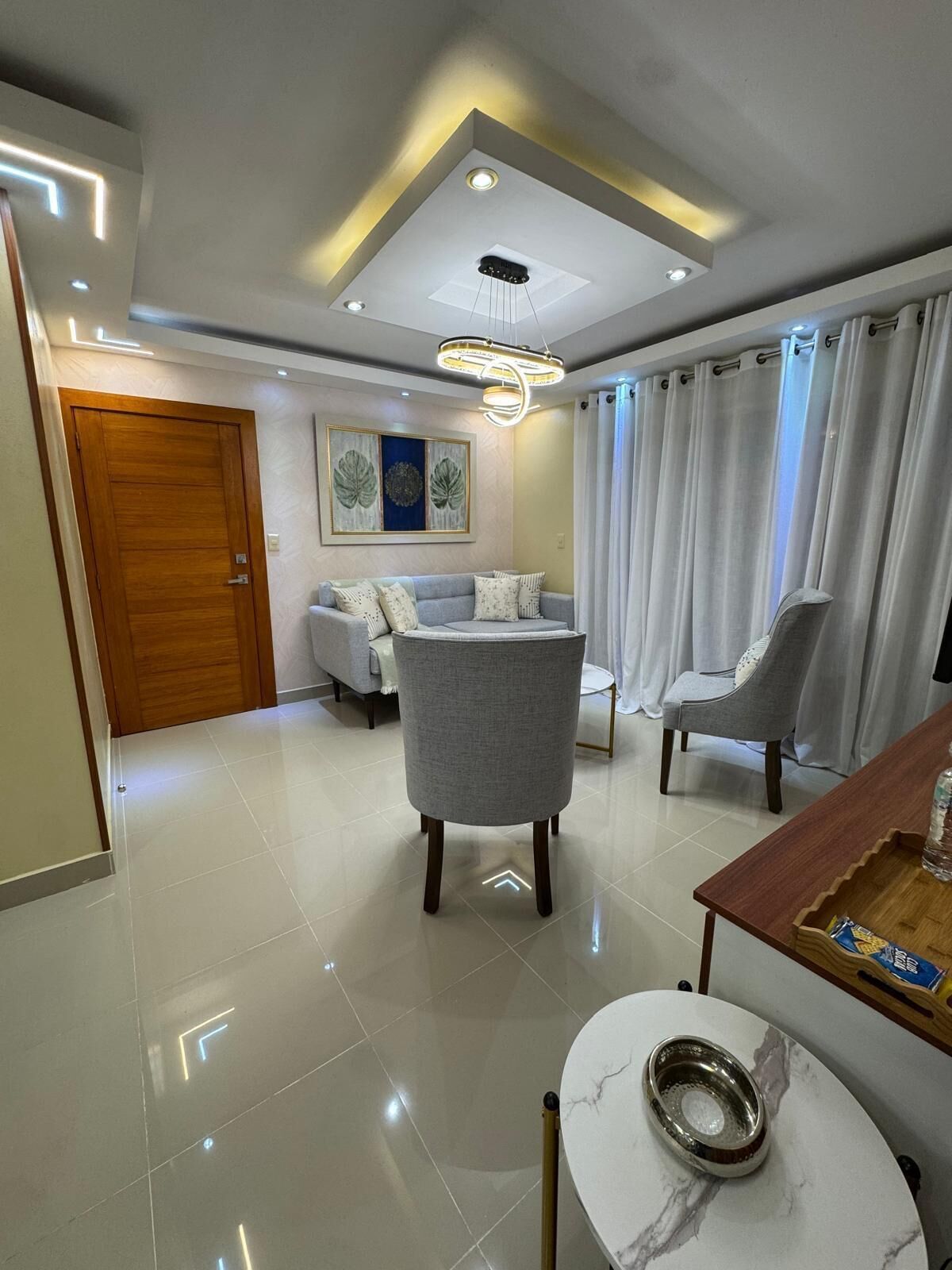 Una sala de estar moderna con un sofá, dos sillones, una mesa de centro y una mesa de comedor.