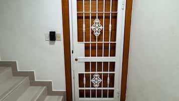 A door with a number plate, a wooden frame, and a decorative metal grille.