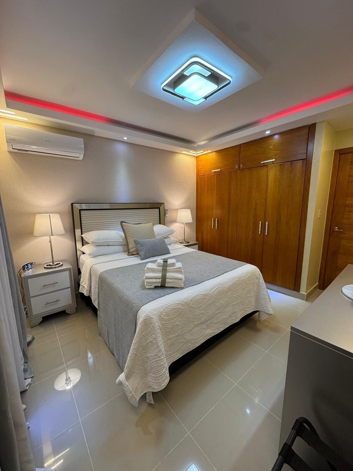 Una habitación de hotel con cama, mesitas de noche, armario y aire acondicionado.