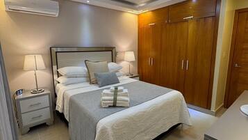 Una habitación de hotel con cama, mesitas de noche, armario y aire acondicionado.