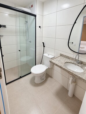 Ein Badezimmer mit einer Duschkabine, einer weißen Toilette und einem Waschbecken mit Granitplatte.