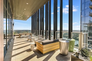 A modern outdoor lounge area with a view of a cityscape, furnished with sofas and chairs, and a patterned floor. - Luxury Lake View 23rd Fl Condo with Private Balcony & Rooftop Pool, Rainey St (Austin)
