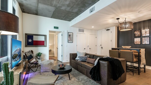 Een moderne woonkamer met een bank, salontafel en een eetgedeelte met stoelen.