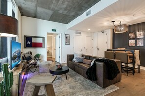 A modern living room with a sofa, coffee table, and a dining area with chairs. - Luxury Lake View 23rd Fl Condo with Private Balcony & Rooftop Pool, Rainey St (Austin)