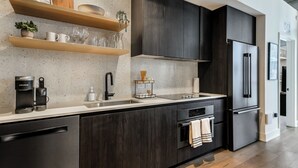 Een moderne keuken met donkere houten kastjes, een roestvrijstalen koelkast en een koffiezetapparaat.