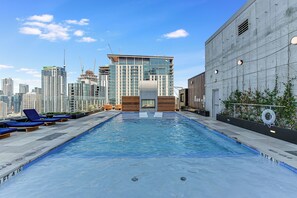 A rooftop pool with a city skyline in the background, lounge chairs, and a building under construction. - Luxury Lake View 23rd Fl Condo with Private Balcony & Rooftop Pool, Rainey St (Austin)