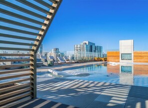 A rooftop pool with a cityscape view, lounge chairs, and a modern building in the background. - Luxury Lake View 23rd Fl Condo with Private Balcony & Rooftop Pool, Rainey St (Austin)