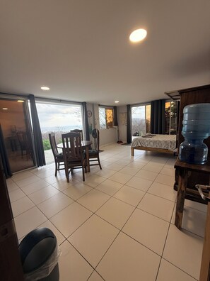A spacious room with a dining area, a bed, and a large water dispenser. - Studio apartment with ocean view, minutes away from the beach, surf, & swimming! (San Juan del Sur)