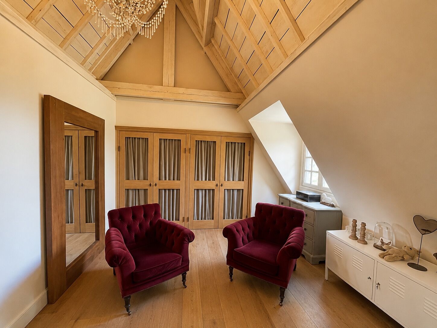 Ein Zimmer mit Holzbalken an der Decke, einem großen Fenster und einem Schrank mit Vorhängen.