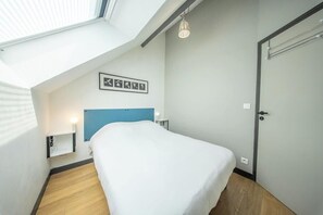 A bedroom with a skylight, a bed, a bedside table, a wall-mounted shelf, and a door. - T2 avec aperçu mer, plage et commerces à pied (Larmor-Plage)