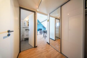 A hallway with a wooden floor leading to a room with a kitchen and a dining area. - T2 avec aperçu mer, plage et commerces à pied (Larmor-Plage)