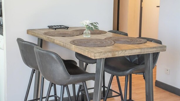 Een eettafel met vier stoelen, een vaas met bloemen en een placemat.
