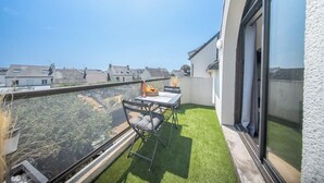 Een balkon met een tafel en stoelen, een klein tuin en uitzicht op de omgeving.