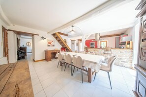 Ein geräumiger Essbereich mit einem langen Tisch und Stühlen, einer Treppe und einer Küchenzeile mit Steinwand.