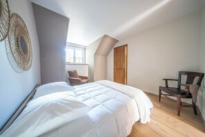 Ein Schlafzimmer mit einem Bett, einem Sessel, einer Tür und einem Fenster.