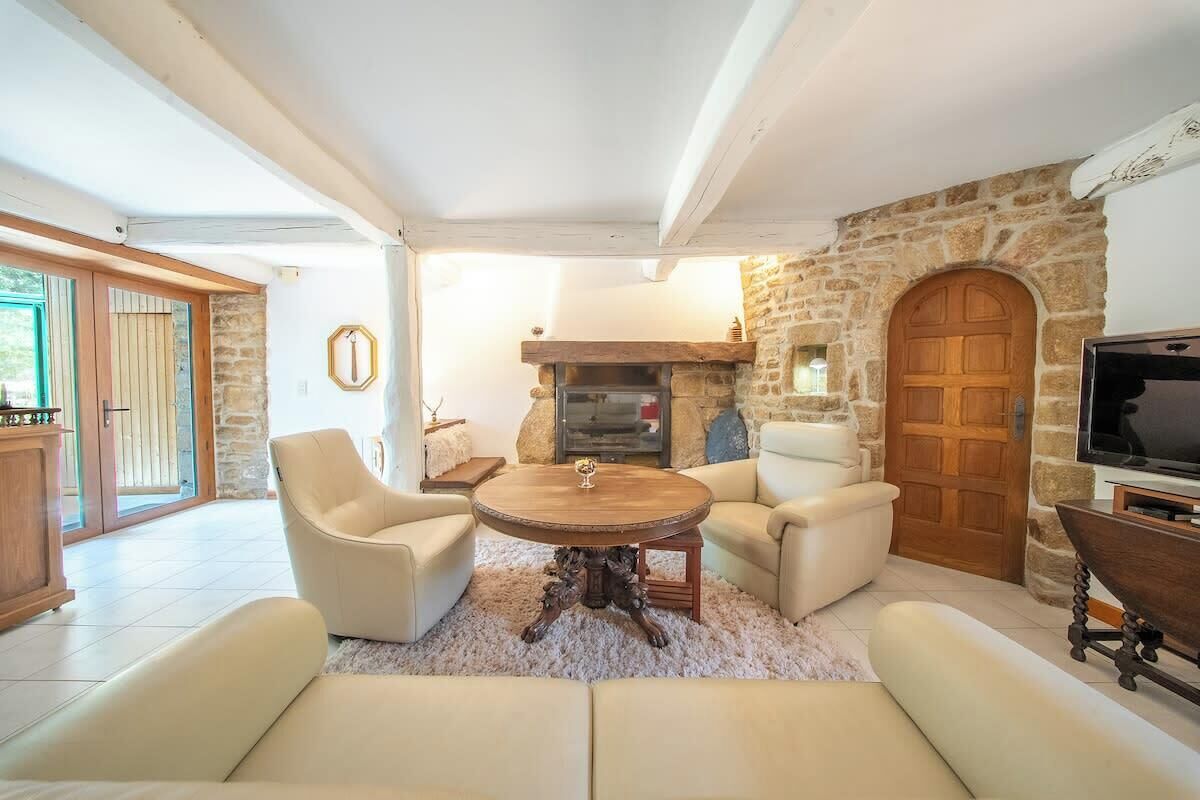 A living room with a stone wall, a fireplace, a television, and a large window.