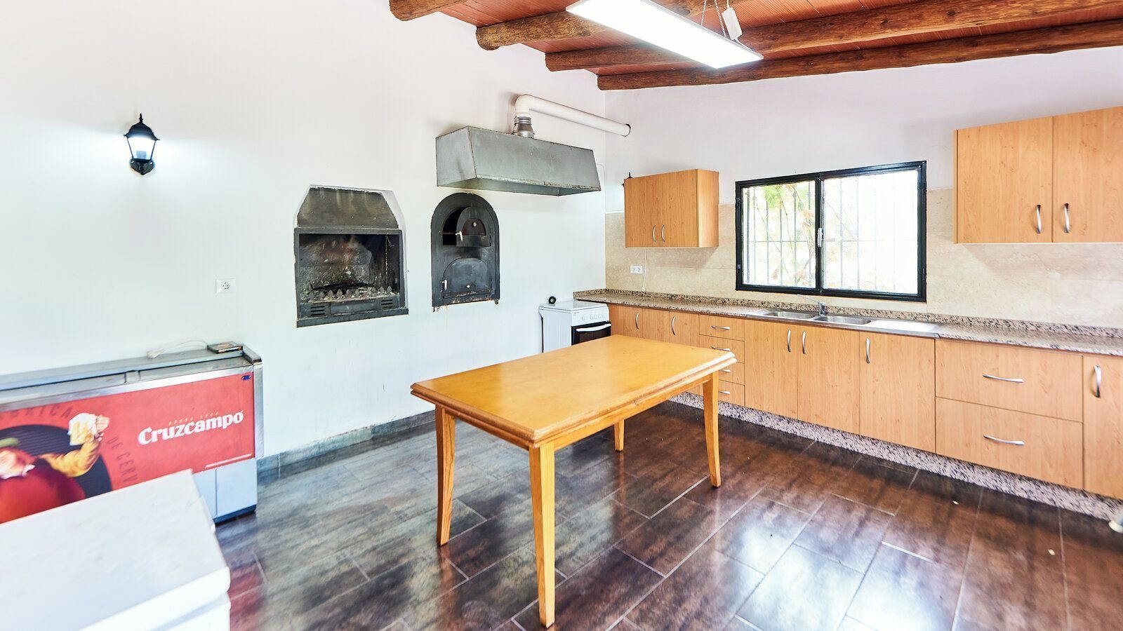 Una cucina con mobili in legno, un tavolo, forno integrato e una finestra.