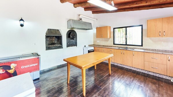 A kitchen with wooden cabinets, a table, a built-in oven, and a window.