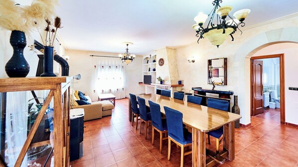 A spacious living area with a dining table, blue chairs, and a sofa.