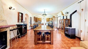 A spacious kitchen with a long wooden table, bar stools, and a built-in oven.